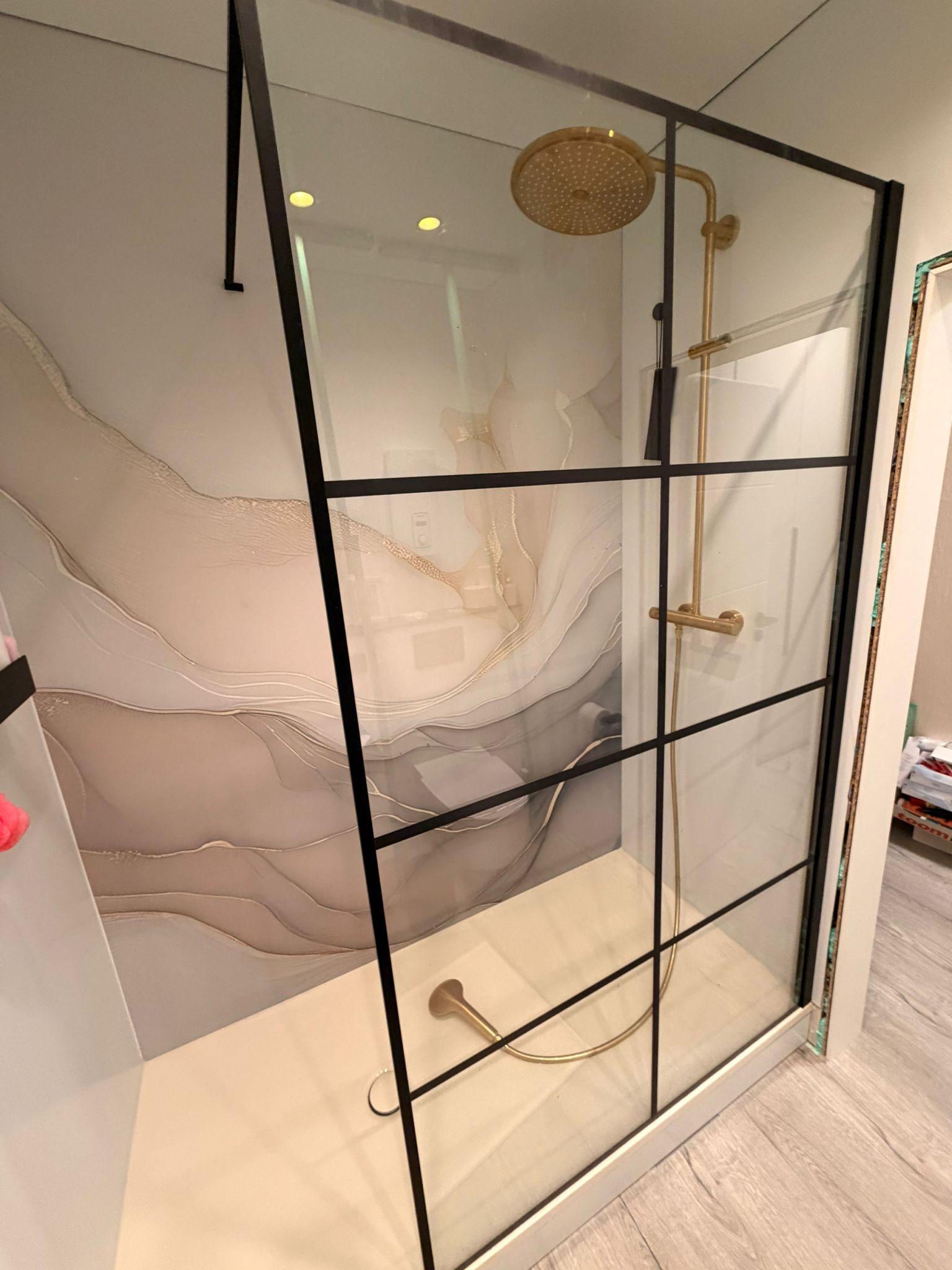 Duschbereich mit schwarzem Glasrahmen und goldfarbenen Armaturen