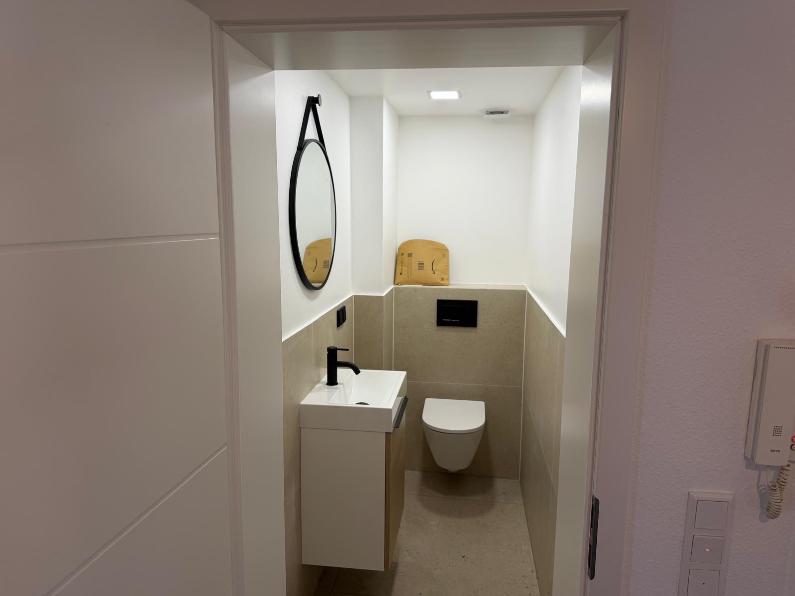 Gäste-WC mit kompaktem Waschtisch und rundem Spiegel